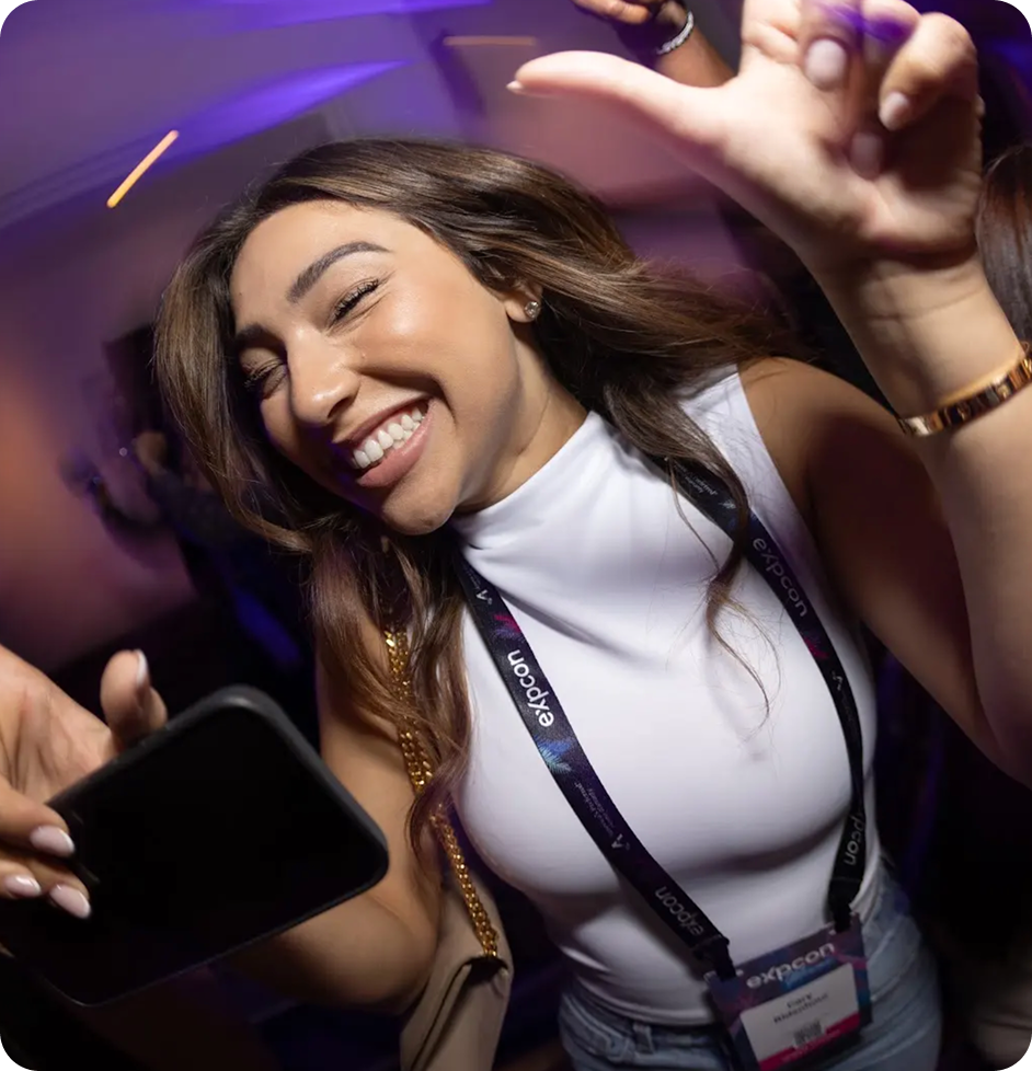 A woman smiling and dancing with a phone in her hand.